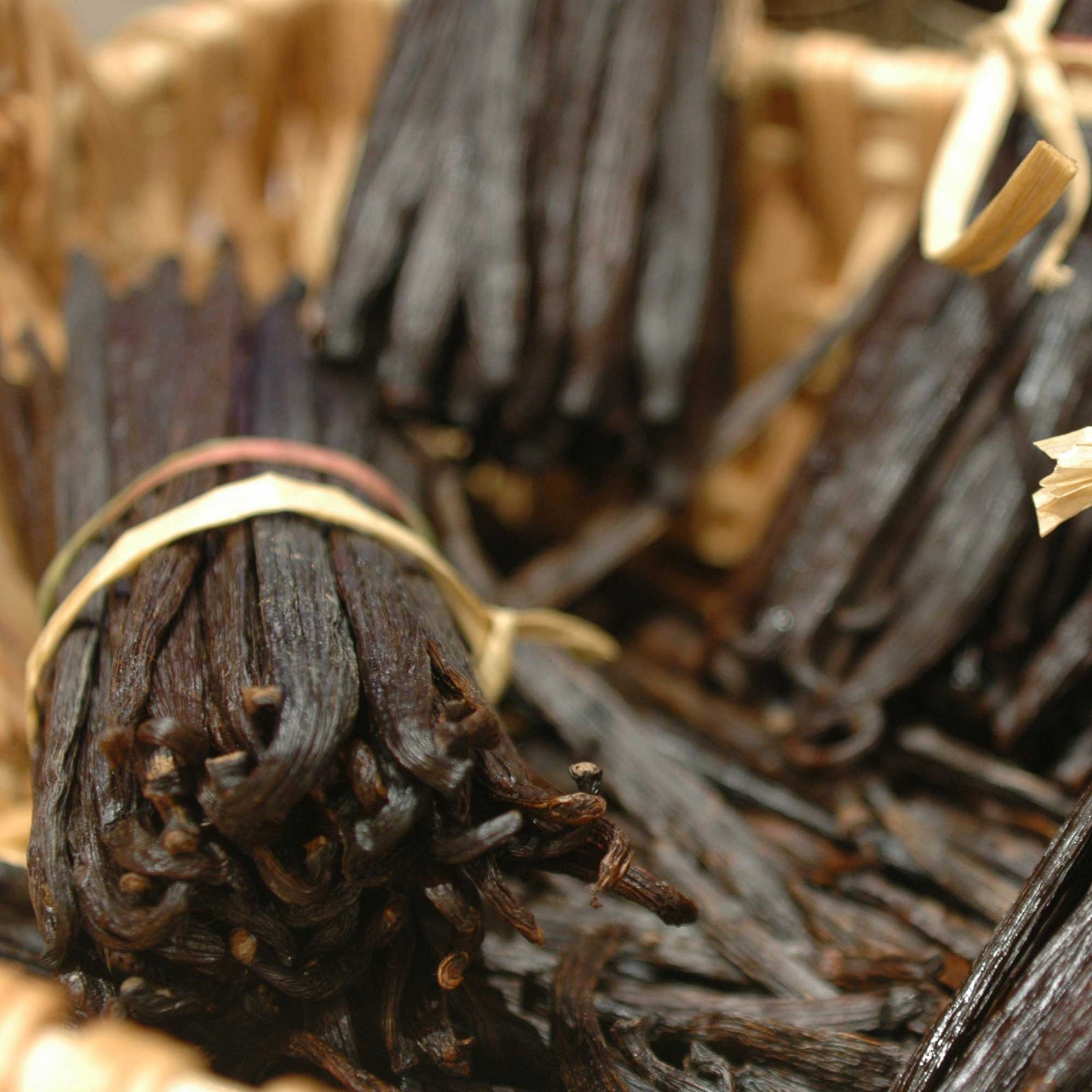 Close-up of vanilla beans tied together with a string on a wooden surface.