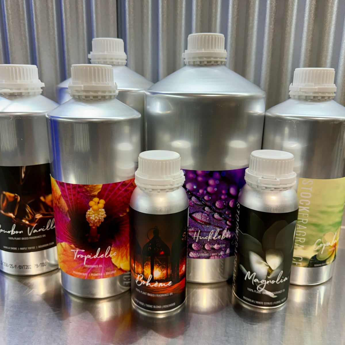 Collection of aluminum stock fragrance oil bottles with colorful labels on a metallic surface