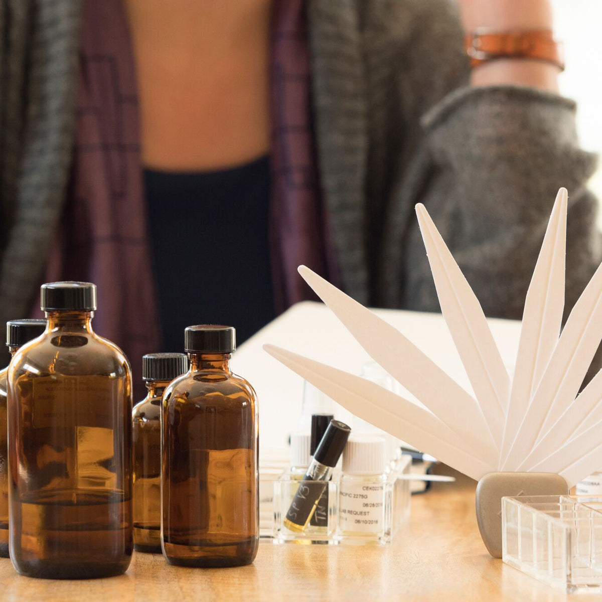 brown perfume bottle and blotters with perfumer in background